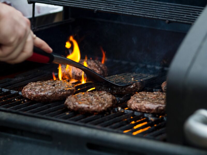 person grilling hamburger patties