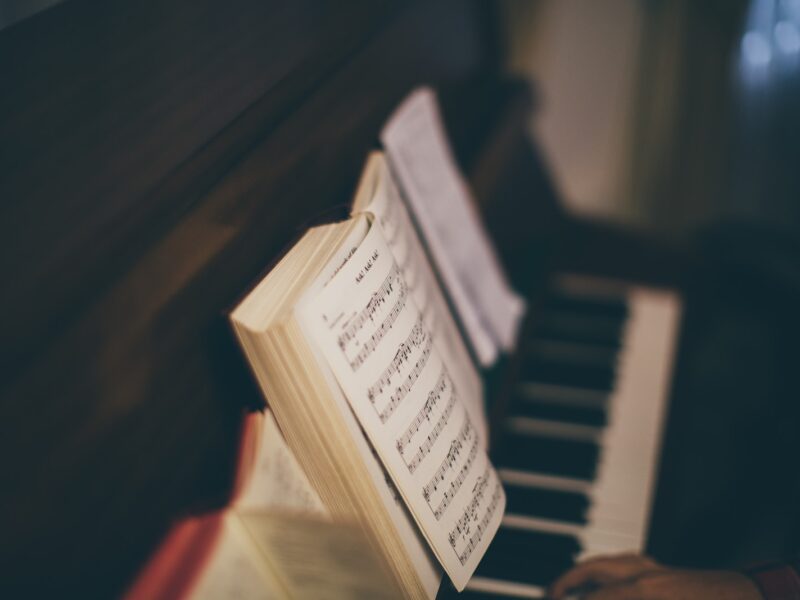 opened music sheet book on top of upright piano