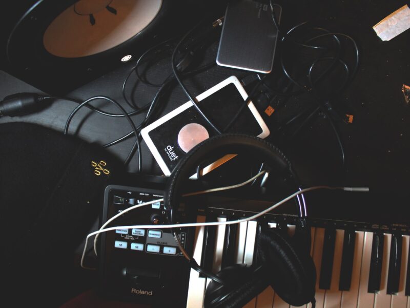 flat-lay photo of headphones, MIDI keyboard, and speaker on black surface