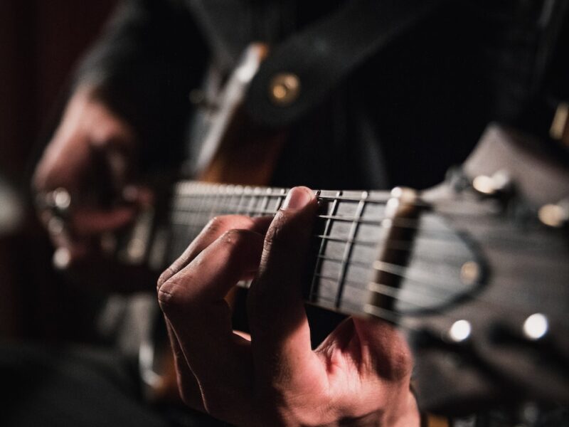 man playing guitar in close up photography