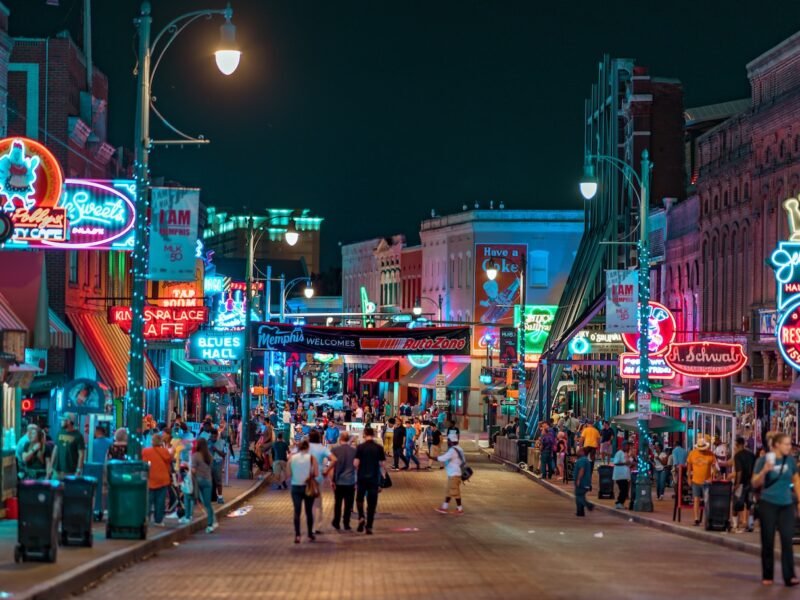 people walking in middle of road in between establishments at night time