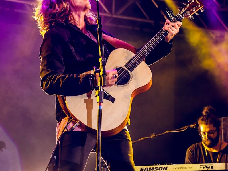 man singing and playing guitar on stage