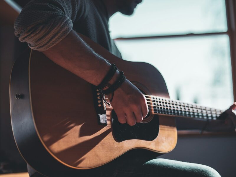 man playing acoustic guitar selective focus photography