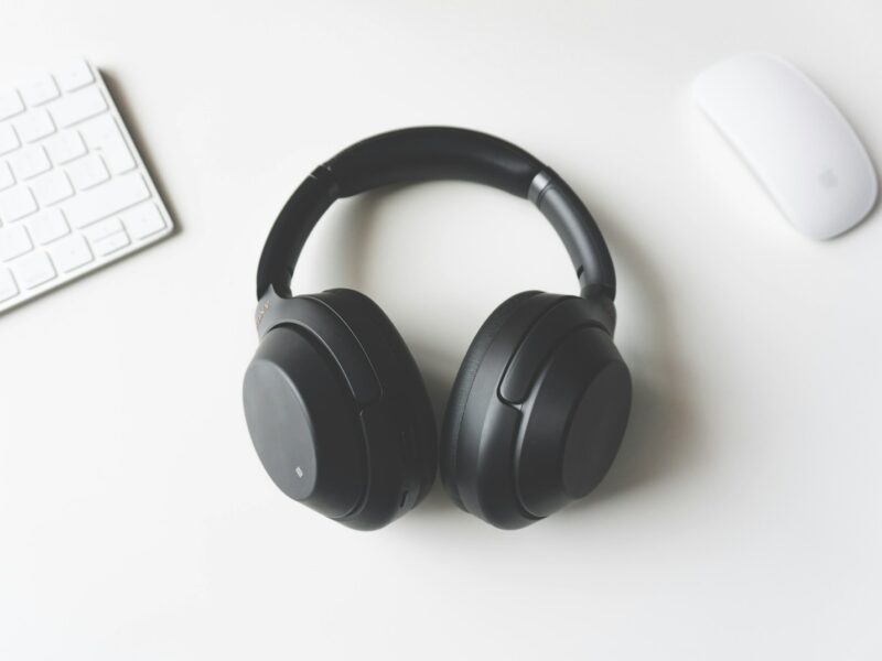 black wireless headphones between Apple Keyboard and Apple Magic Mouse on white surface