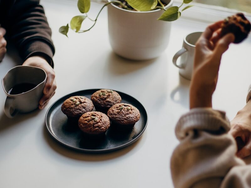 person holding brown and black round food on white ceramic plate