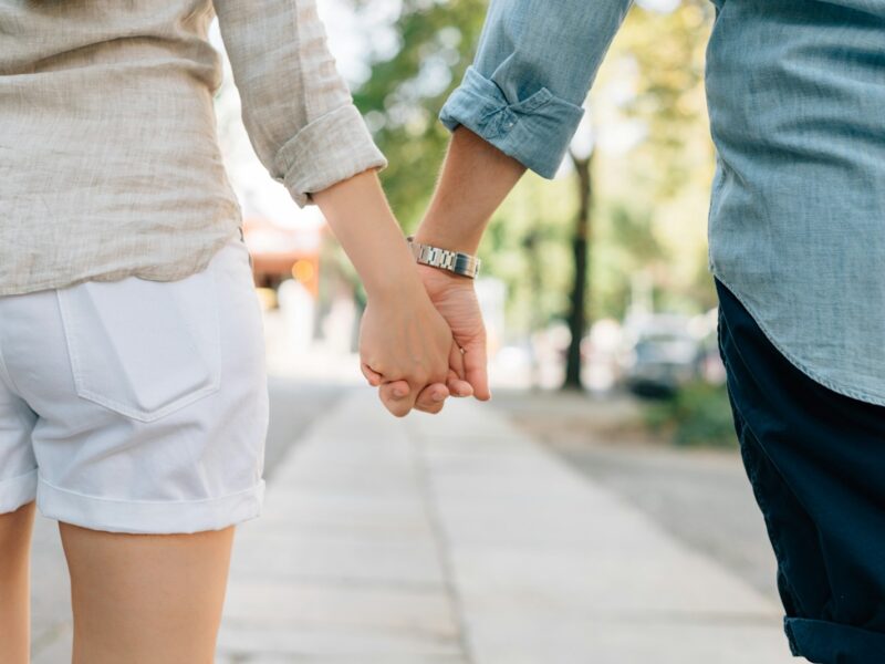 man and woman holding hands together in walkway during daytime