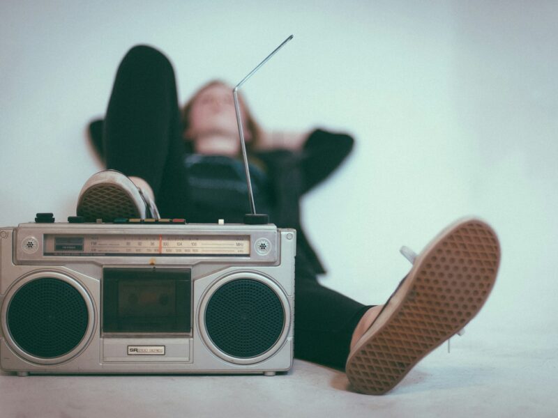 woman laying on bed near gray radio