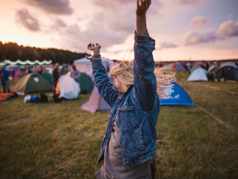 a woman raising her arms in the air in front of tents