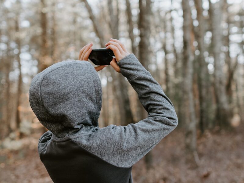 man in gray sweater holding black camera