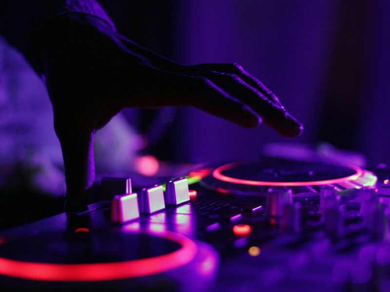 selective focus silhouette photography of man playing red-lighted DJ terminal