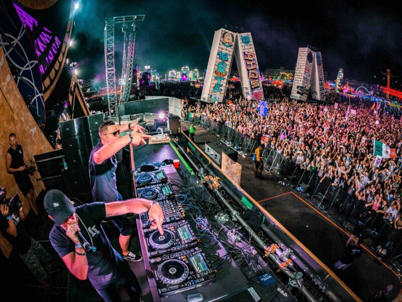 two men playing DJ controllers at night time